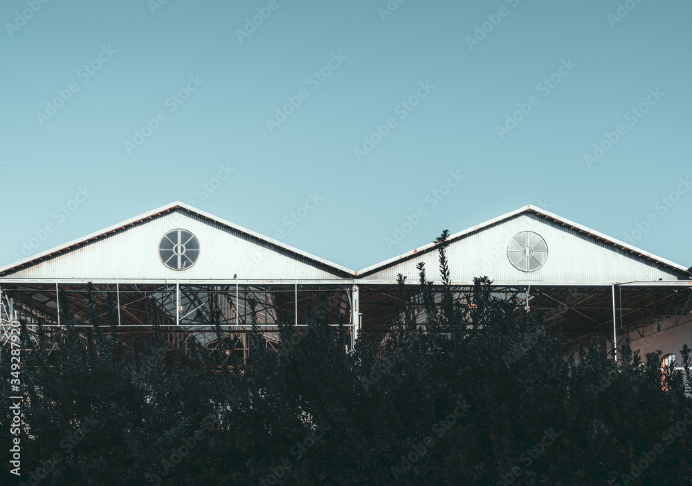 An outdoor view of two triangle metal roofs with a single round window ...