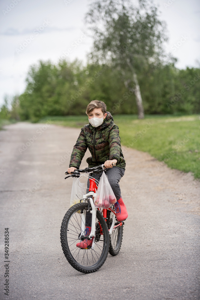 Masked boy and red boots carry apples home. Virus protection. Health concept Masked boy and red boots carry apples home. Virus protection. Health concept