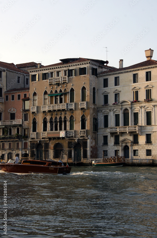 Photo of Grand canal in Venice with historical facades made in baroque and renaissance styles with balustrades,  piles, boats in sunny summer day.