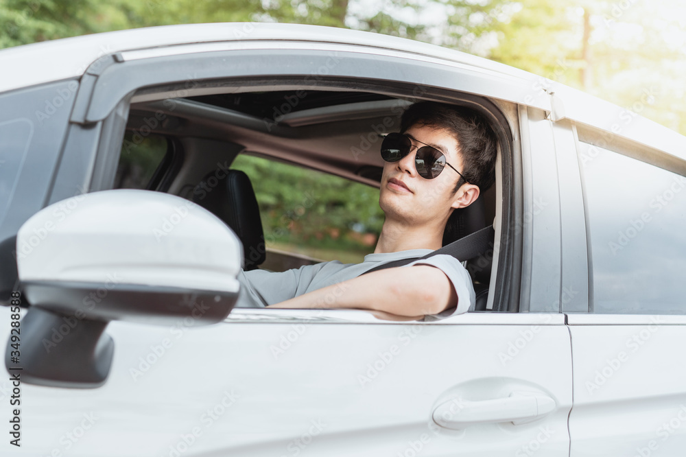 The male driver wearing sunglasses resting against the car window