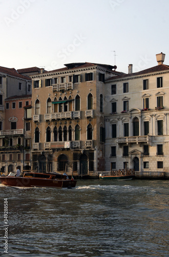 Photo of Grand canal in Venice with historical facades made in baroque and renaissance styles with balustrades, piles, boats in sunny summer day.