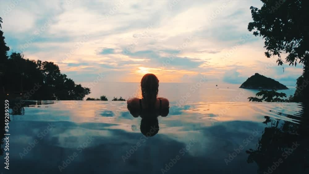 beautiful girl gazing out of luxurious infinity pool
