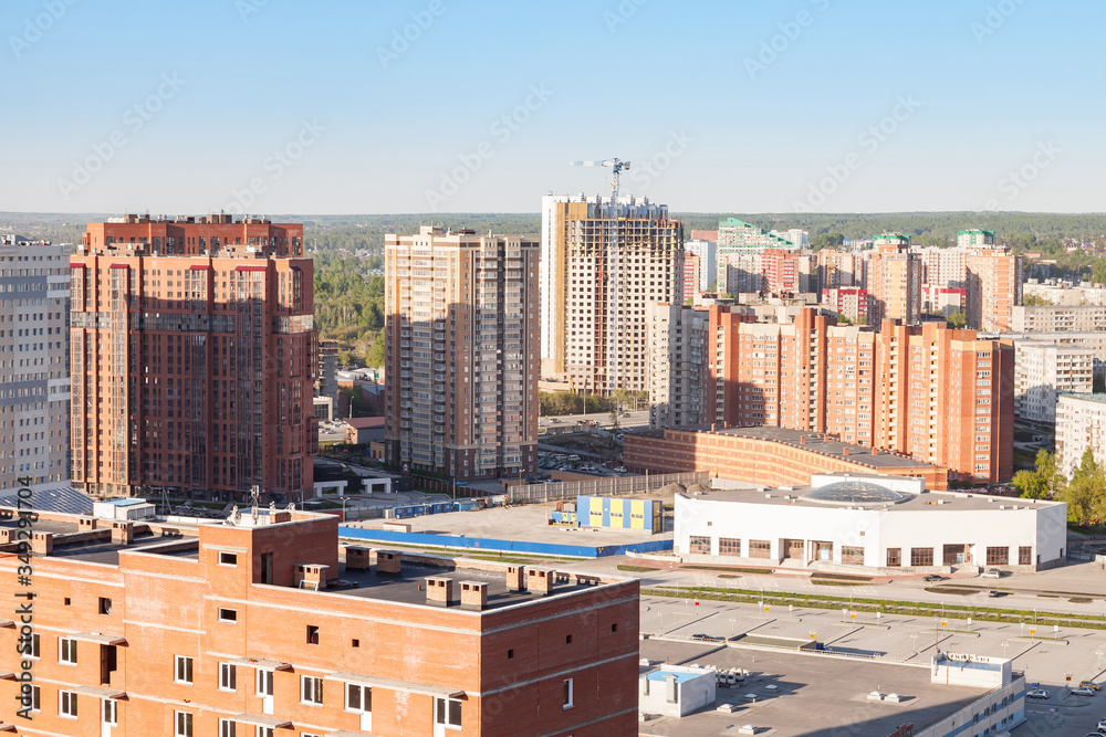 Fototapeta premium A new family-friendly neighborhood with tall buildings made of brown brick and a large garage with multi-level parking, a building project that meets the requirements of the mortgage market.