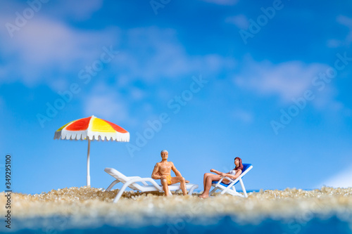 Miniature people sunbathing on The beach , Summer time concept © Sirichai Puangsuwan