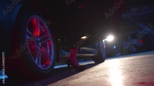 The girl in high heels gets out of the car. Low angle