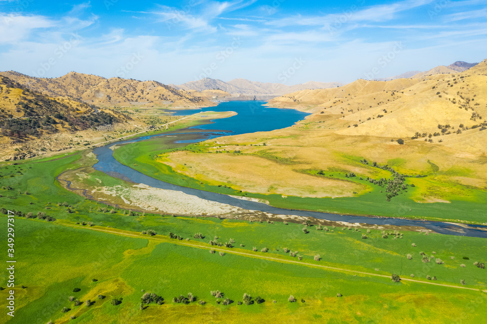 Fototapeta premium Aerial nature top view of Lake Kaweah Recreation Area outside of Sequoia National Park. Green grass, blue sky, yellow mountains, morning, blue water. Autumn landscape. California, USA