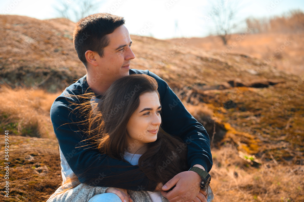 Lovely young couple spending their time on a journey trip. Sweet beginning of relationships. Travel outdoors during golden hour on a grassy plain. Sun light on faces, strong wind blows hair. Lovely young couple spending their time on a journey trip. Sweet beginning of relationships. Travel outdoors during golden hour on a grassy plain. Sun light on faces, strong wind blows hair.