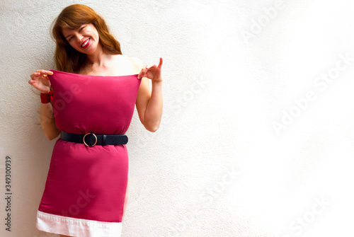 Happy Woman in red pillow dress smiling on white wall background. Fashion girl. Pillow Challenge due to home isolation. Caronavirus Quarantine. photo