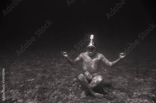 Snorkeler Is meditating, snorkeling man in full face mask, summer vacation activity, swimming in the warm tropical sea, seashore and fishes, starfishes near rocks, Italyю Black and white