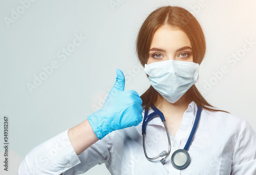 Covid19, coronavirus, a concept of healthcare and doctors. Portrait of an optimistic female doctor assures that everything will be fine, thumbs up photo