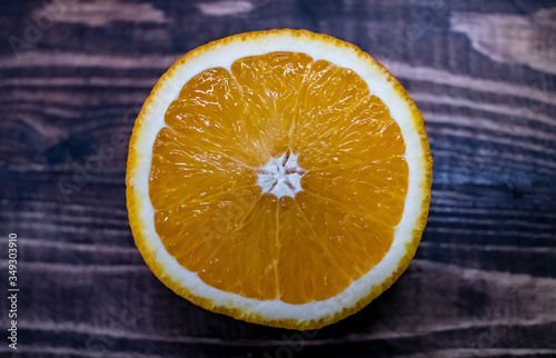 Sliced orange in abstract style on wooden background. Grunge texture background. Poster design. Nature background. Sweet fruit. Design element. Concept of product design. Tropical fruit