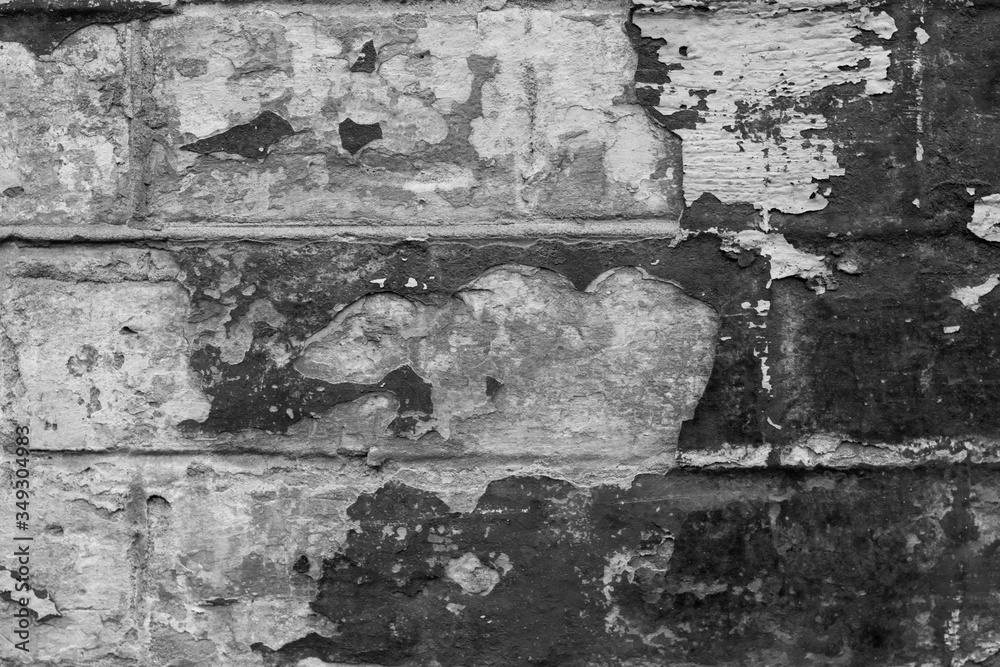 Black and white photo of bricks with peeling old paint. Photo trending texture was shot close-up for your design.