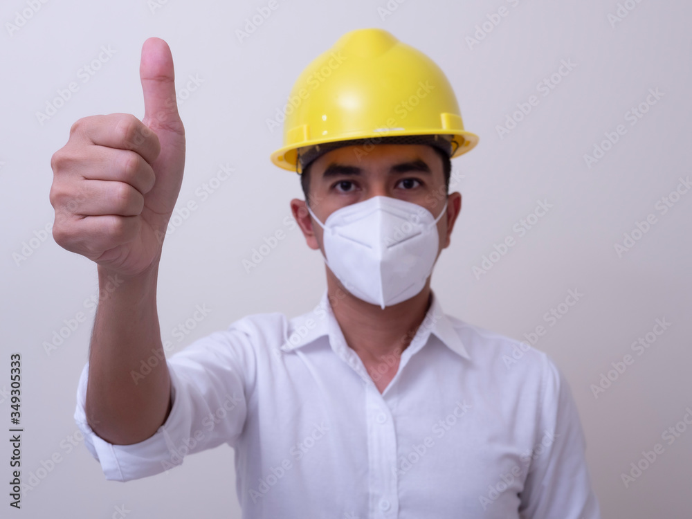 Asian industrial workers wear yellow hard hats, wear protective masks for their health Asian industrial workers wear yellow hard hats, wear protective masks for their health