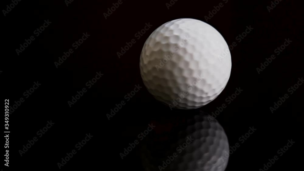 Golf ball white color turn rotating on black background with reflection.