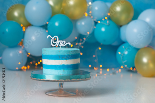 blue cake striped on a stand and balloons