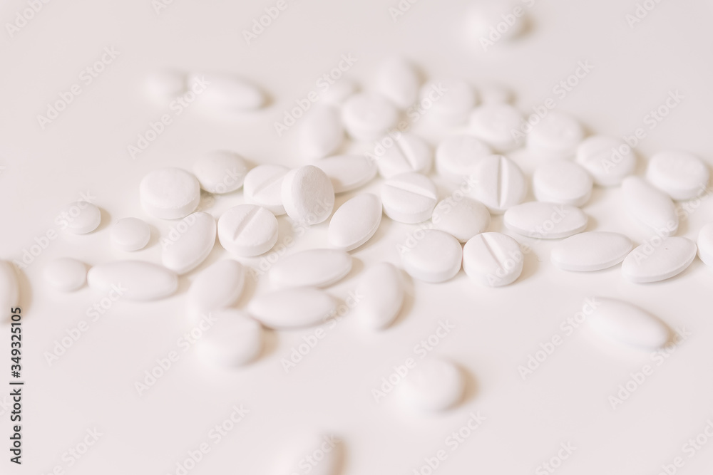 Pile of white pills on white background.