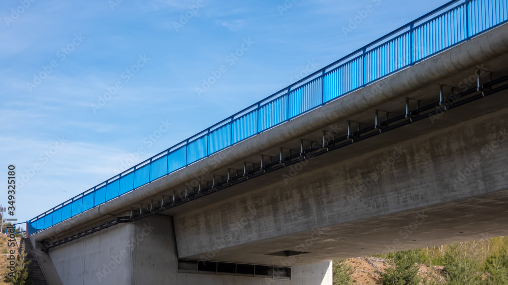 Neue Betonbrücke vor blauem Himmel und blauem Geländer Neue Betonbrücke vor blauem Himmel und blauem Geländer