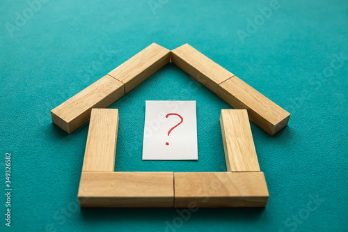 House made of wooden blocks with a red question mark inside on a blue background. Low angle view, close-up.