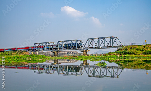 A bridge over water body with train passing over it, Assam India, reflection in water photo