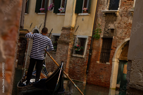 Venice gondolier rides tourists through the canals of Venice.