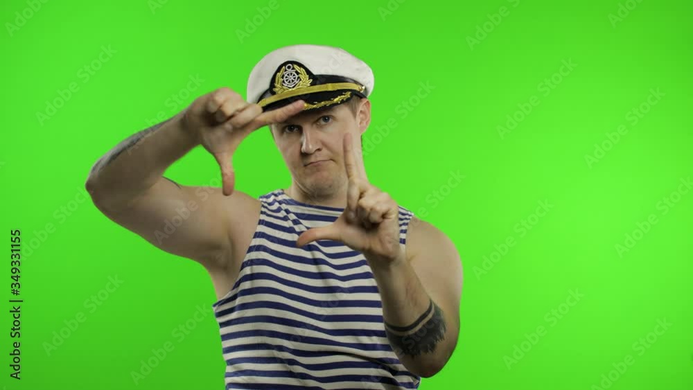 Young sailor man takes a photo on a retro camera. Seaman guy in sailor's vest Young sailor man takes a photo on a retro camera. Seaman guy in sailor's vest
