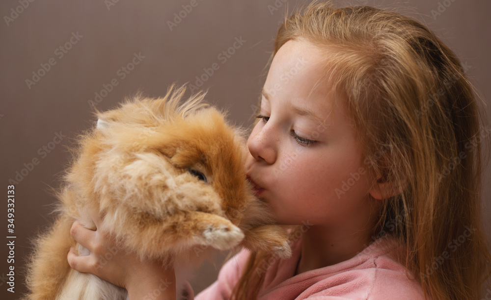Redhead girl child kisses a rabbit. Redhead girl child kisses a rabbit.