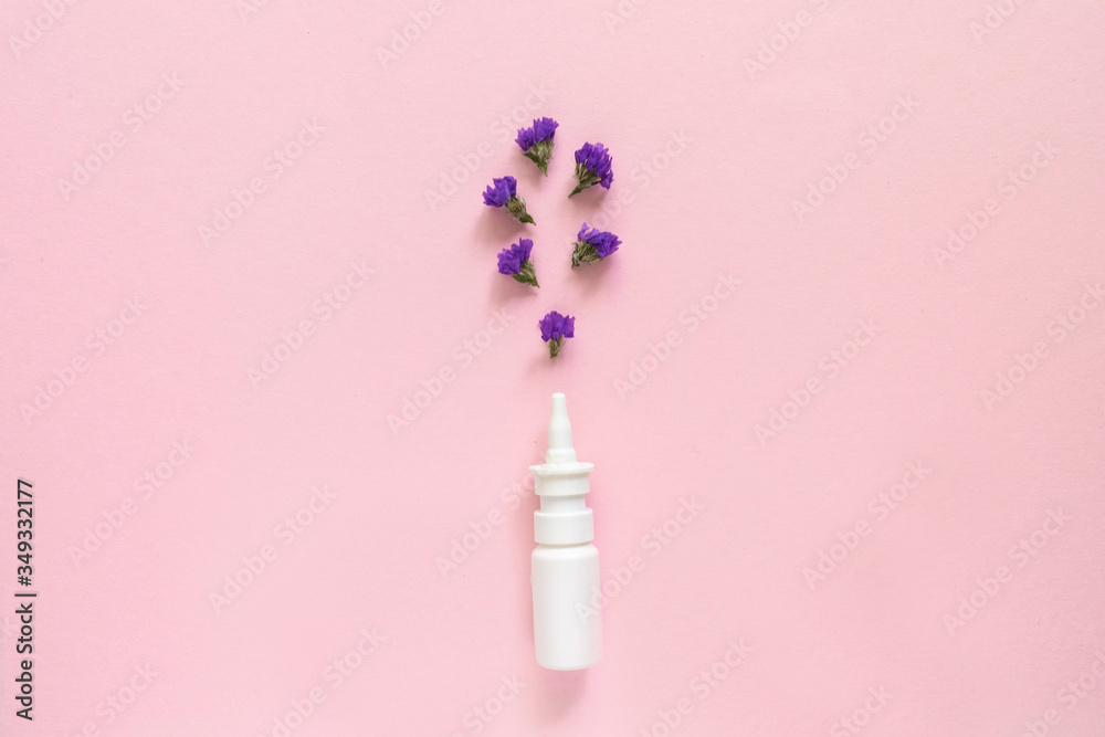 Seasonal spring summer allergy flowers concept. White spray container with purple flowers on pink background. Creative flat lay composition, copy space