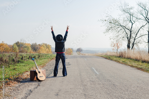 Фотография Lonely guitarist looking at empty country road in autumn.
