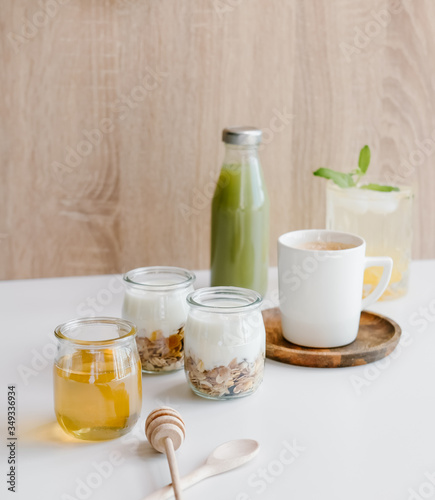 Healthy breakfast set with coffee, homemade yogurts with granola, honey or agave syrup and green juice. 