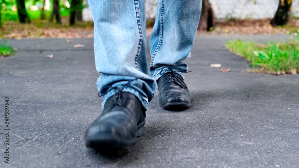 View of man's walking legs in blue jeans, black leather shoes. View of man's walking legs in blue jeans, black leather shoes.