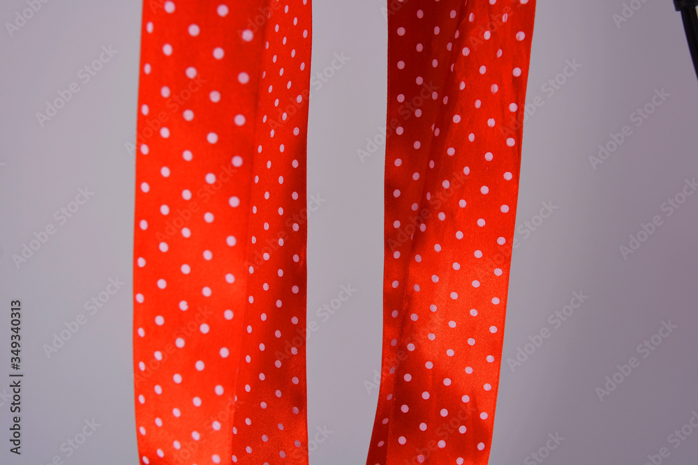 Red ribbon with white polka dots located on a white background. A wide colorful elegant wide ribbon curled in an interesting way. Red ribbon with white polka dots located on a white background. A wide colorful elegant wide ribbon curled in an interesting way.