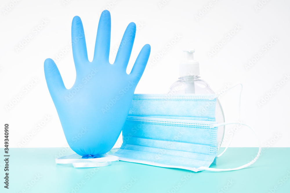 Inflated nitrile disposable glove with a protective medical mask and a plastic bottle of antibacterial hand sanitizer gel - a virus spread protection kit. Stop coronavirus concept. Inflated nitrile disposable glove with a protective medical mask and a plastic bottle of antibacterial hand sanitizer gel - a virus spread protection kit. Stop coronavirus concept.