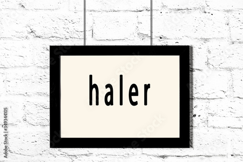 Black frame hanging on white brick wall with inscription haler photo