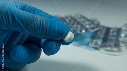 doctor holds a pill from the virus in his hands. Pandemic Covid 19. White tablet in the palm of a blue medical glove. Close-up