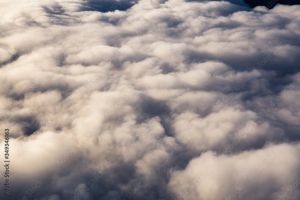 Aerial view from above a white and puffy clouds during a sunny sunrise. Taken from Airplane in British Columbia, Canada. Aerial view from above a white and puffy clouds during a sunny sunrise. Taken from Airplane in British Columbia, Canada.