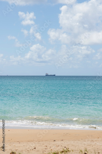 Beautiful day at the beach in focus in the far off distance there is a cargo vessel