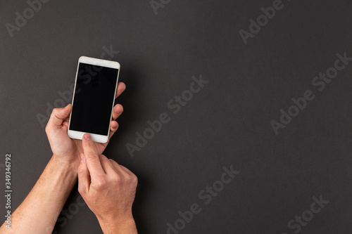 Hands touching blank screen smartphone on abstract black background with copy space