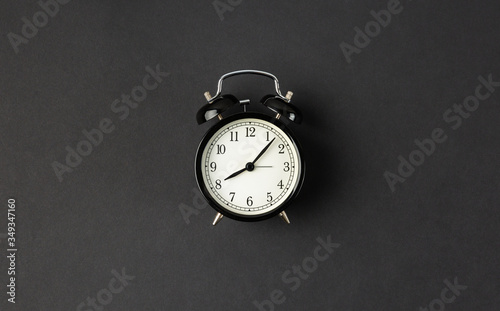 Classic alarm clock on abstract black background with copy space