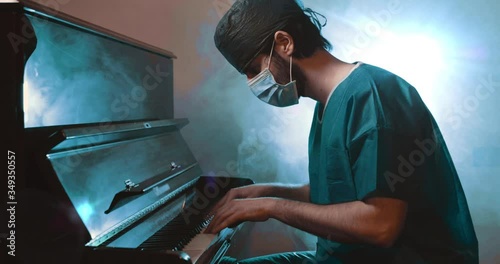 Medico o chirurgo in divisa suona il pianoforte per rilassarsi photo