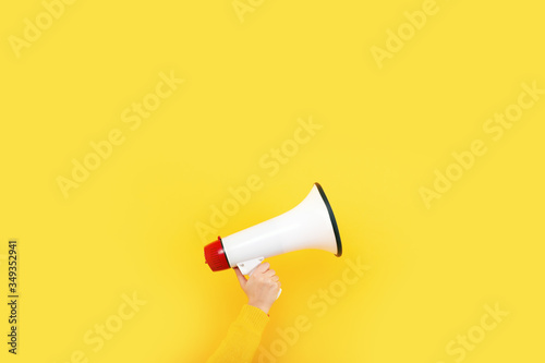 megaphone in hand on a yellow background, advertising concept