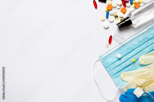 Medical mask, sanitizer bottle, pills, white white and blue medical gloves, thermometer on a white background. The concept of protecting health from the virus. Copy space, top view. 