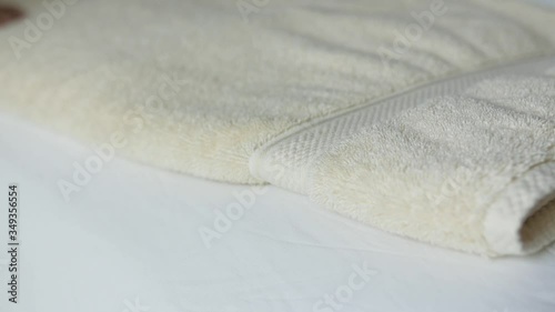 Lady smoothing out cream bath towel and folds it.