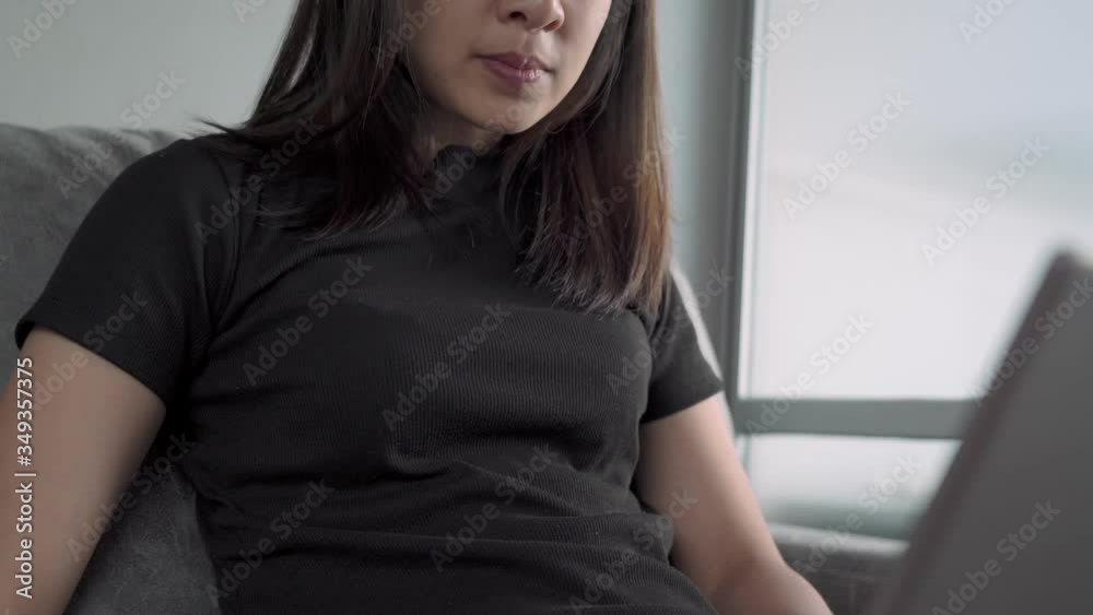 Asian lady looking down at laptop computer, at home living room sitting on sofa, work on her project, home quarantine covid-19, decision making, economic financial crisis, job searching opportunity Asian lady looking down at laptop computer, at home living room sitting on sofa, work on her project, home quarantine covid-19, decision making, economic financial crisis, job searching opportunity