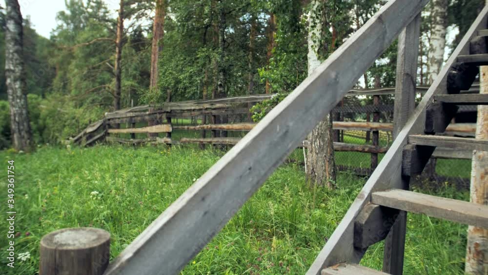 Close-up shooting of an old wooden staircase and fence in summer weather. Old farm fence close-up. Close-up shooting of an old wooden staircase and fence in summer weather. Old farm fence close-up.