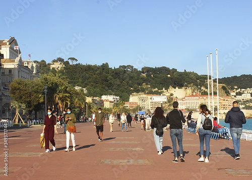 people walking and wearing face masks in the city of nice, france