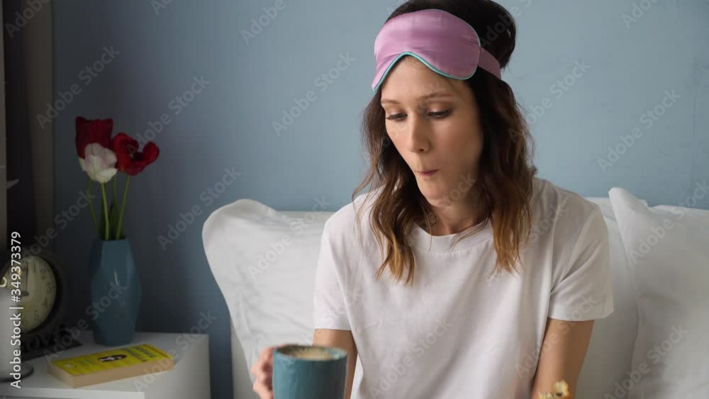 Young beautiful woman eats biscuits and drinks coffee in bed for breakfast. Good morning concept Young beautiful woman eats biscuits and drinks coffee in bed for breakfast. Good morning concept