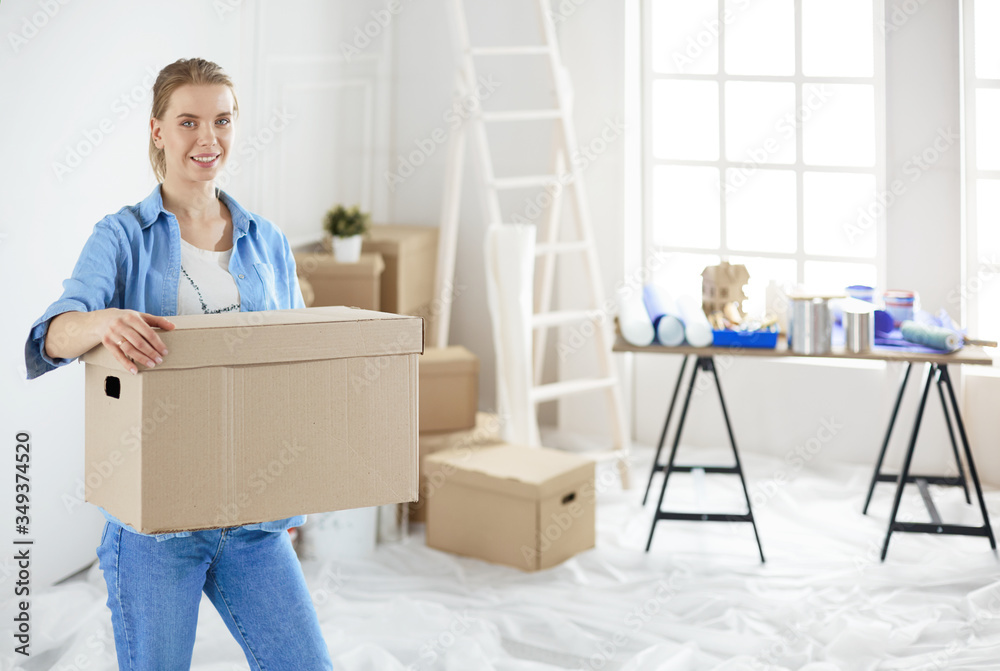 Young woman moving house to new home holding cardboard boxes Young woman moving house to new home holding cardboard boxes