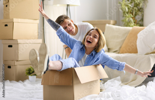 Happy couple having fun and riding in cardboard boxes at new home © lenets_tan