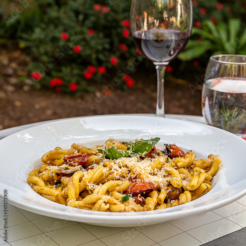 Mesa con plato de pastas y ravioles italianos con copa de vino tinto.