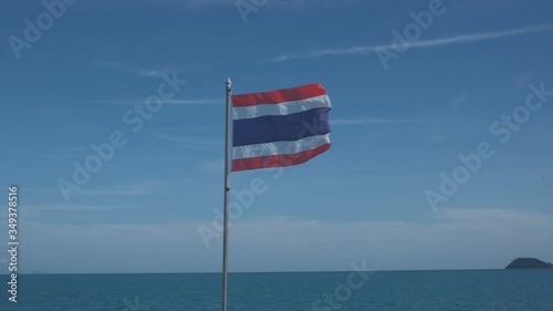 Thai flag flutters in slow motion with a blue sky in the background in the middle of the sea